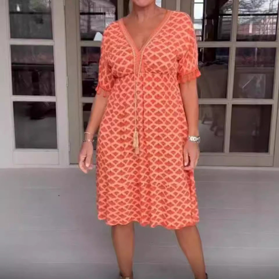 Damklänning midi – avslappnad passform – V-ringning med tofsdetalj – geometriskt mönster